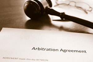 An arbitration agreement lying on a desk beside of a gavel.